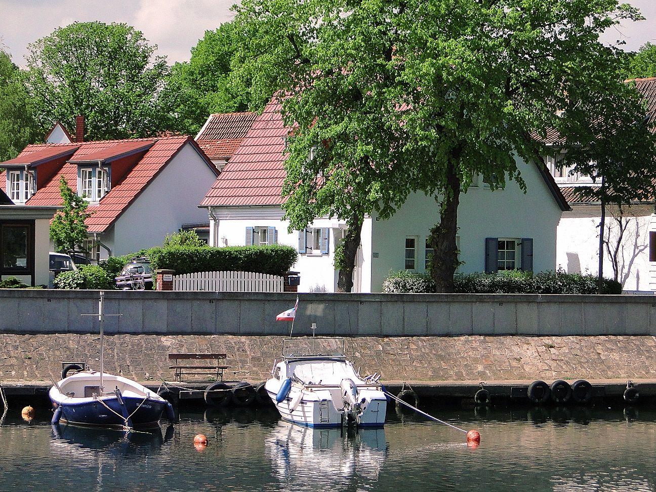 Großes Kreuzfahrtschiff liegt am Hafen mit modernem Kai und blauem Himmel.