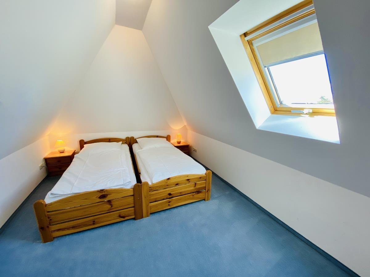 Treppenhaus mit Holzgeländer führt zu einem Schlafzimmer mit Dachfenster und Bett.
