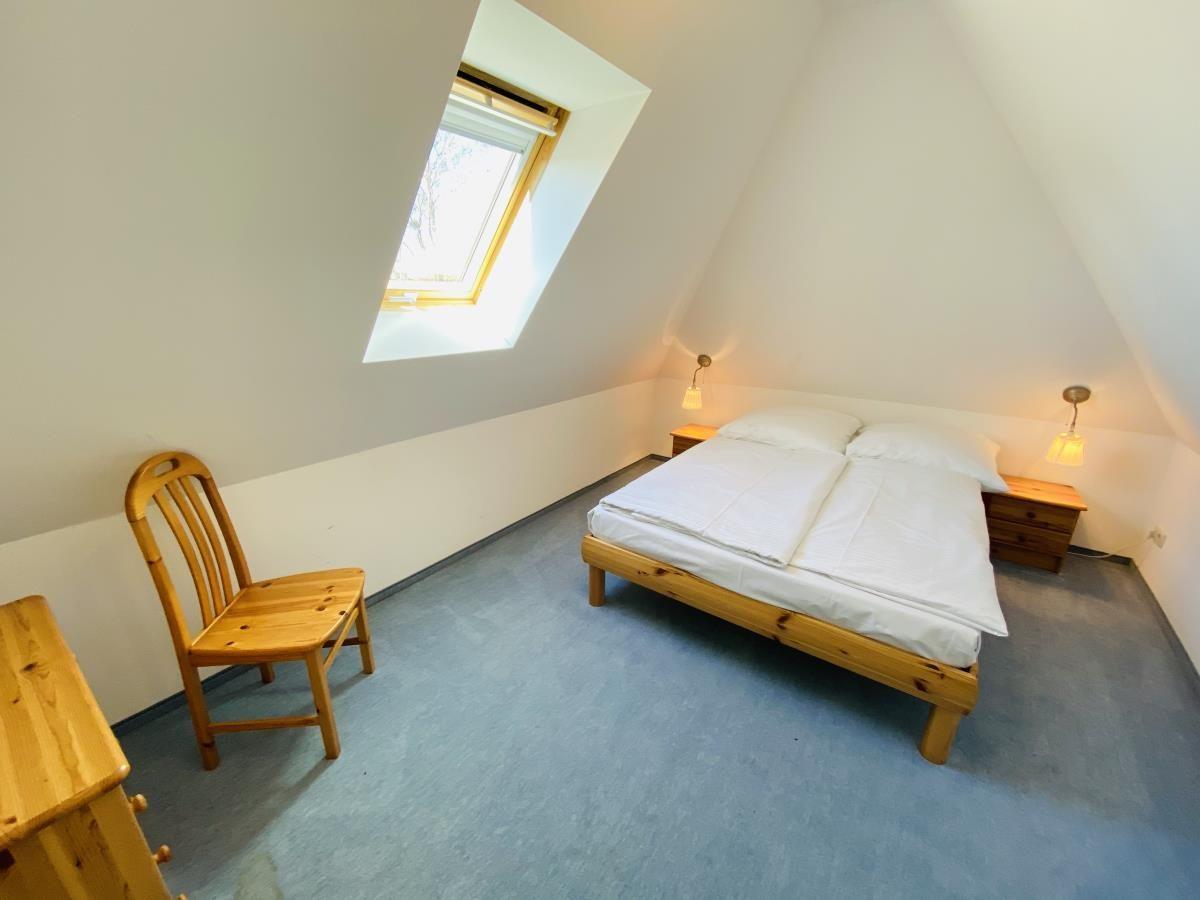 Badezimmer mit Dusche, Waschbecken und Toilette. Fenster und Dachschräge.
