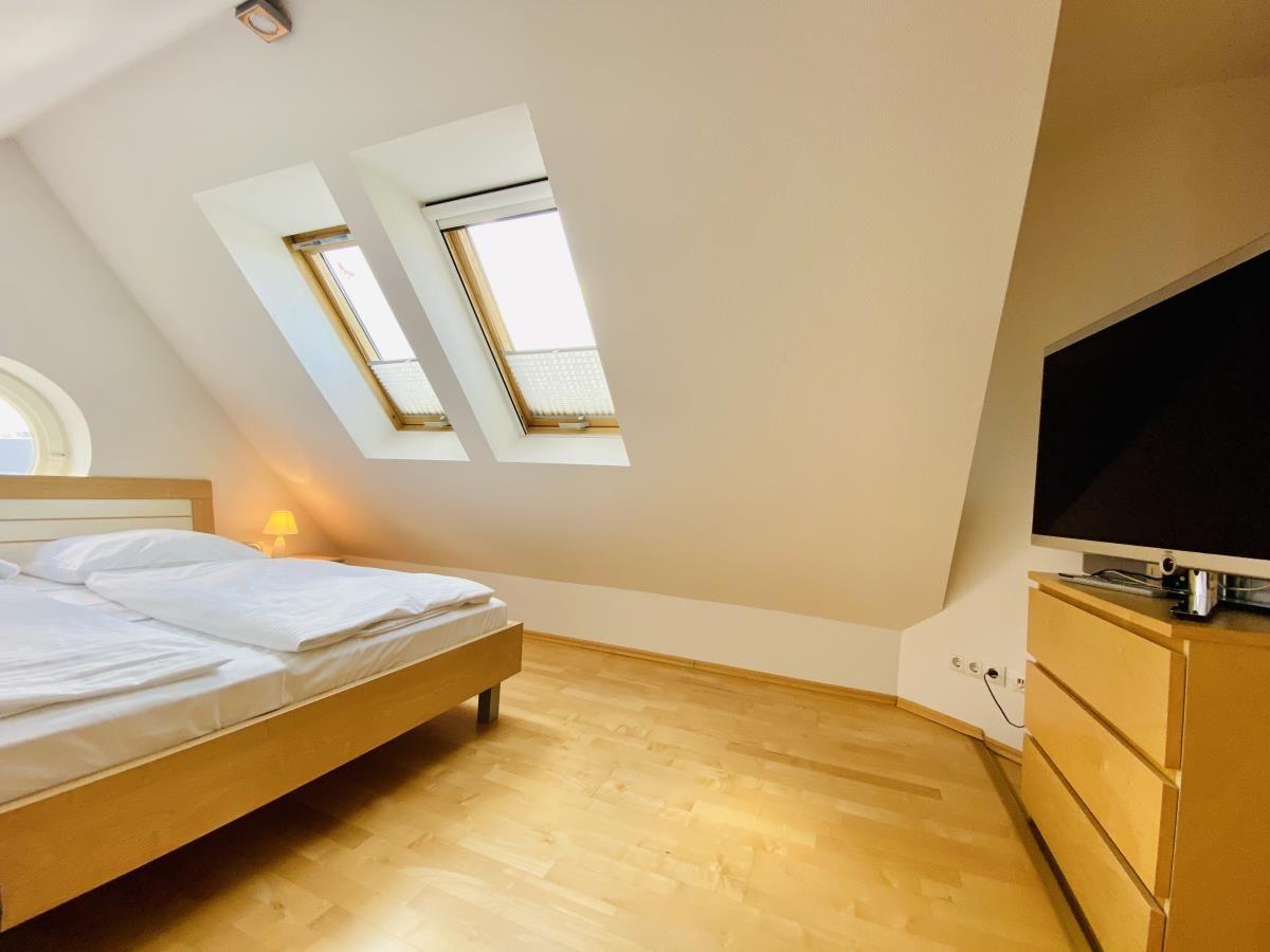 Ein Schlafzimmer mit Bett, Sofa und Fernseher an der Wand.