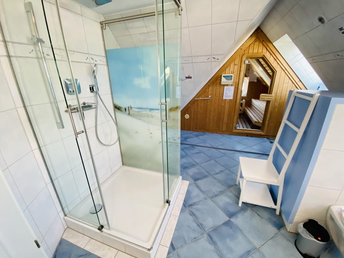 Sauna mit Rundfenster, Blick auf Strand und Meer, Holzbucket und Steine sichtbar.