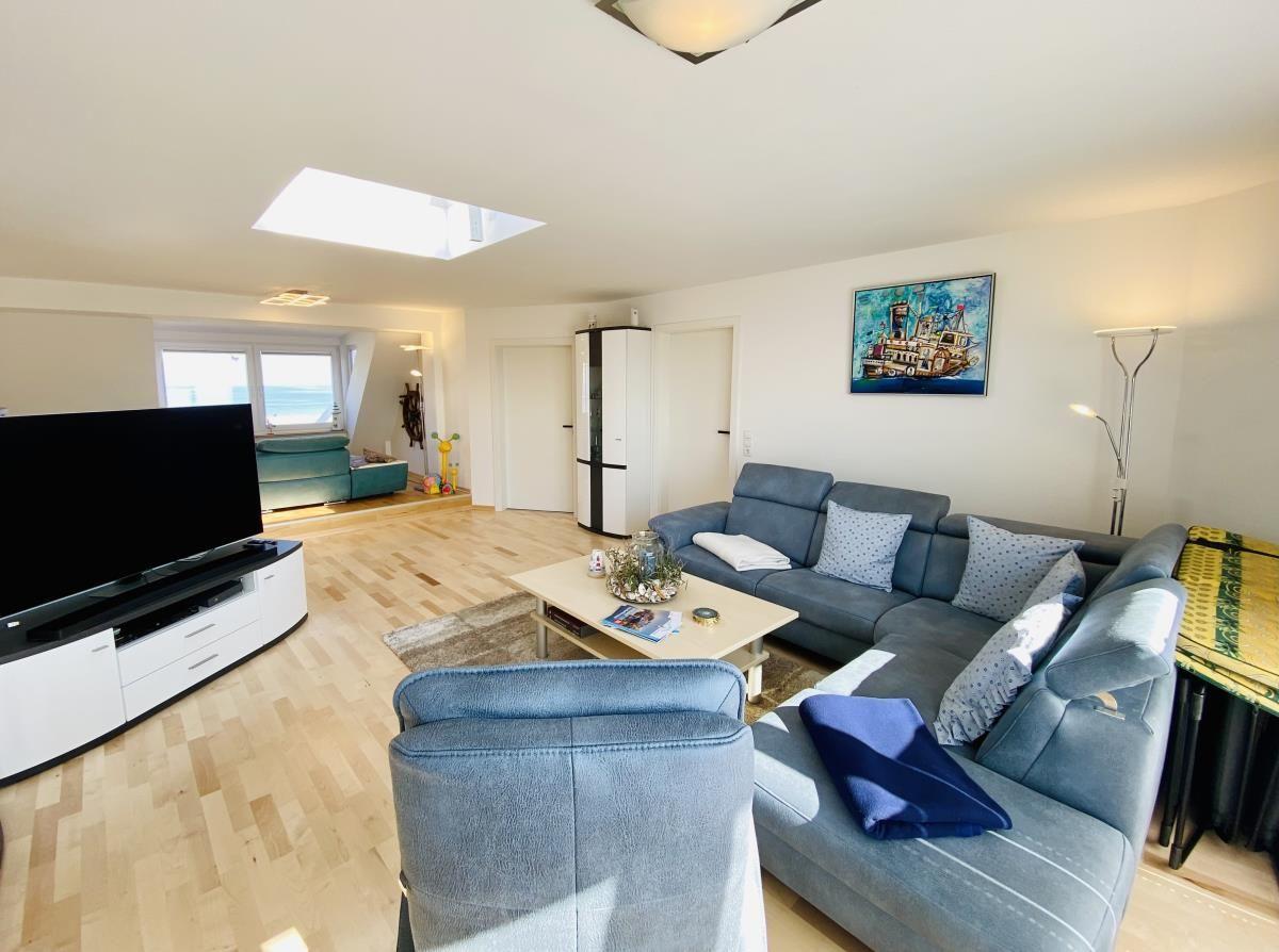 Schlafzimmer mit Blick aufs Meer, hölzerner RuderRad an der Wand, blaues Bett und Holzboden.