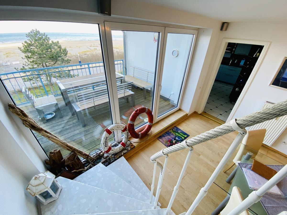 Küche mit Essbereich, Tisch, Stühle und Fenster. Fliesenboden und weiße Schränke.