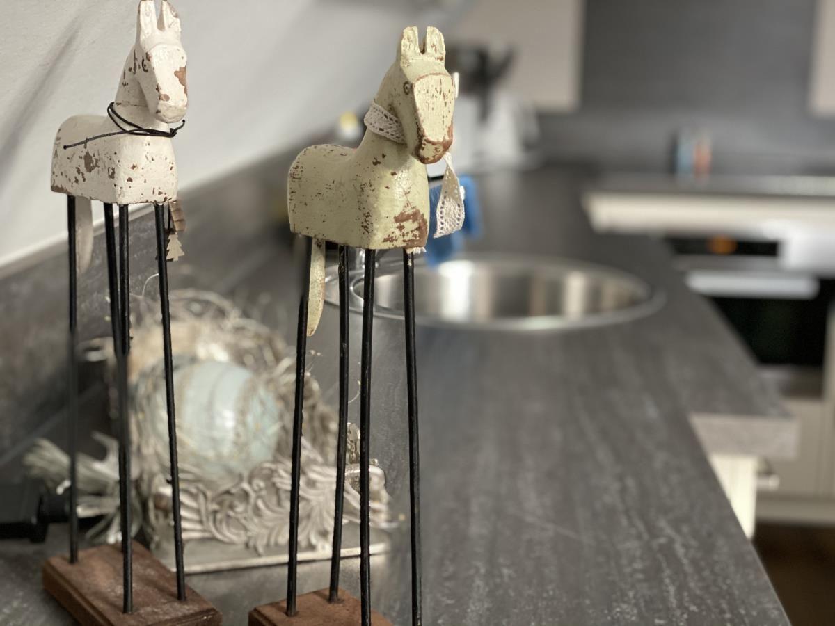 Zwei bunte Hausfiguren und ein gestreifter Sternstuhl auf einem Regal.