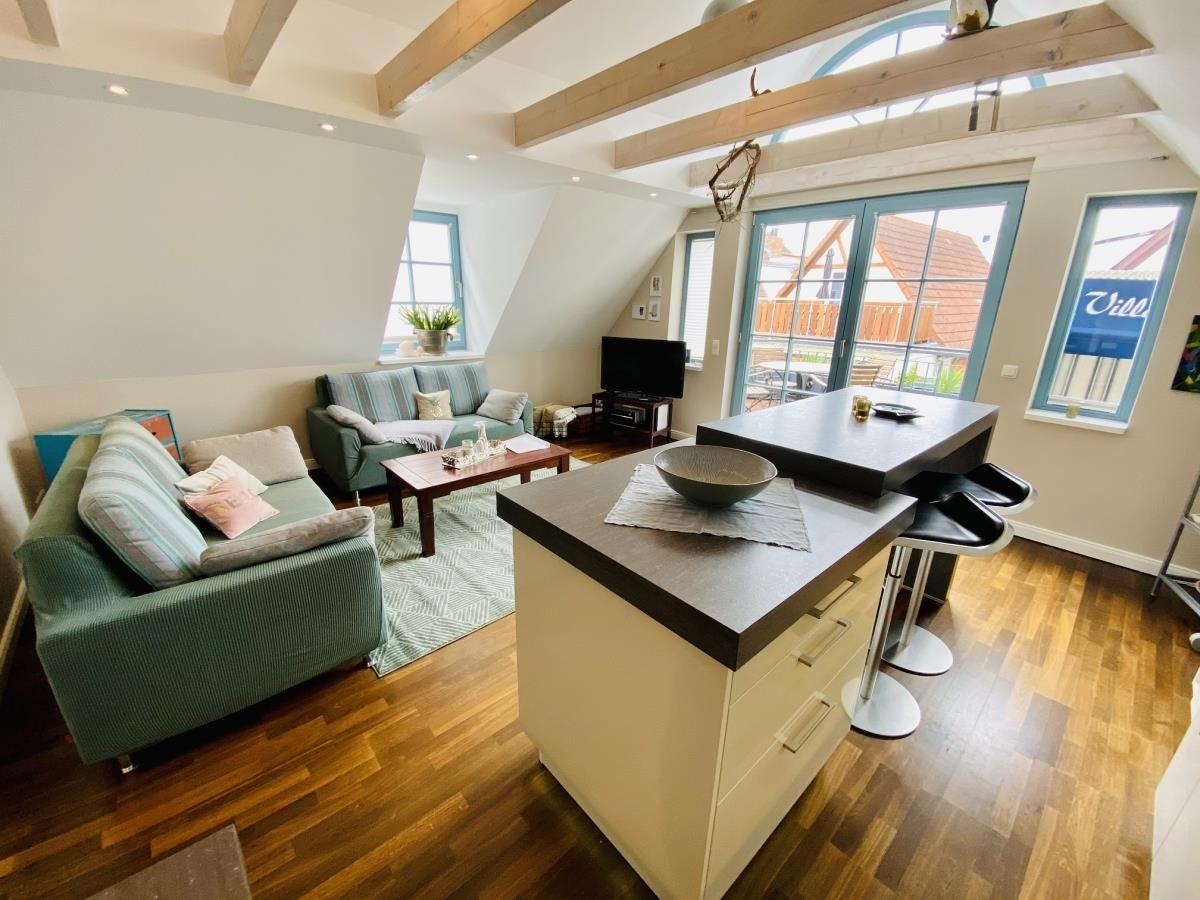 Küche mit Barhocker und Glasfrontschrank. Holzboden und graue Arbeitsplatte.