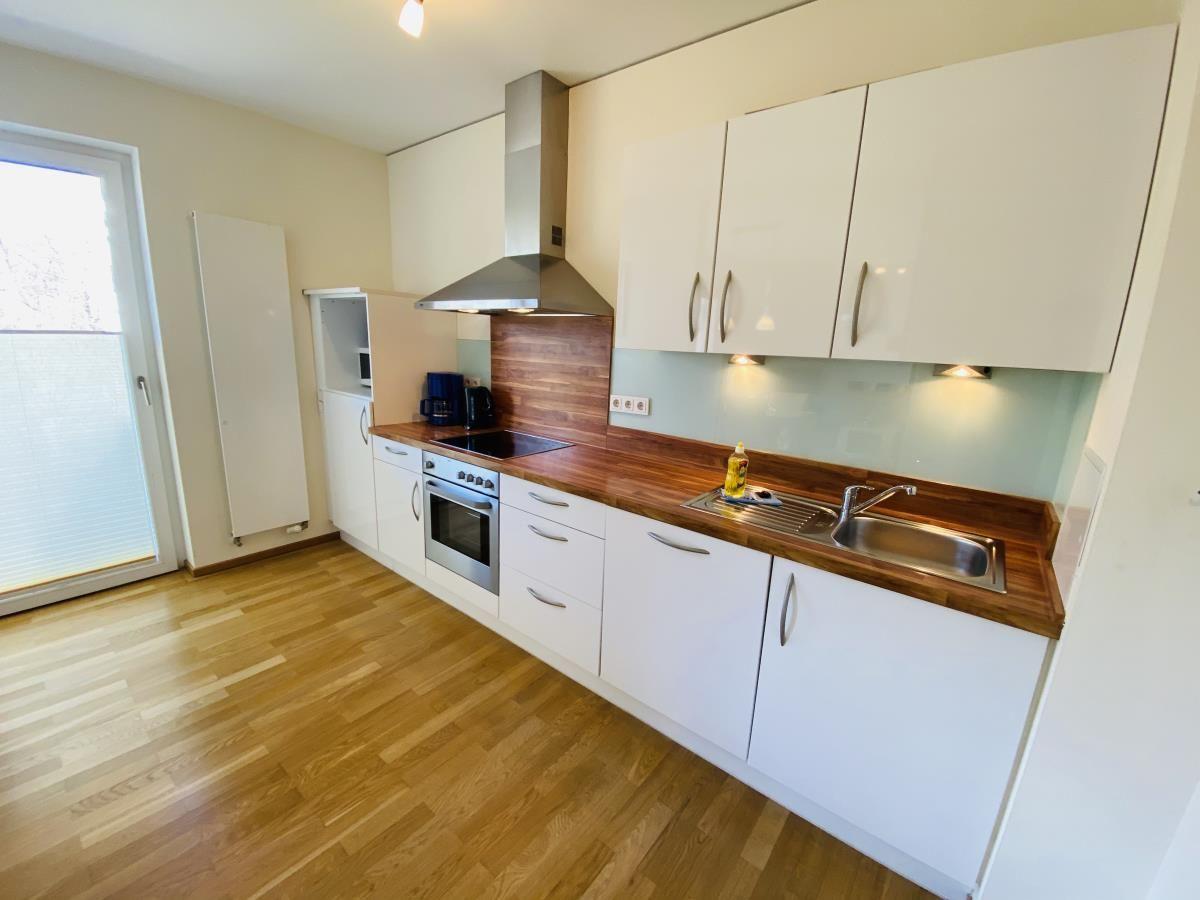 Schlafzimmer mit Bett, Kleiderschrank und TV. Holzboden und Fenster mit Vorhängen.