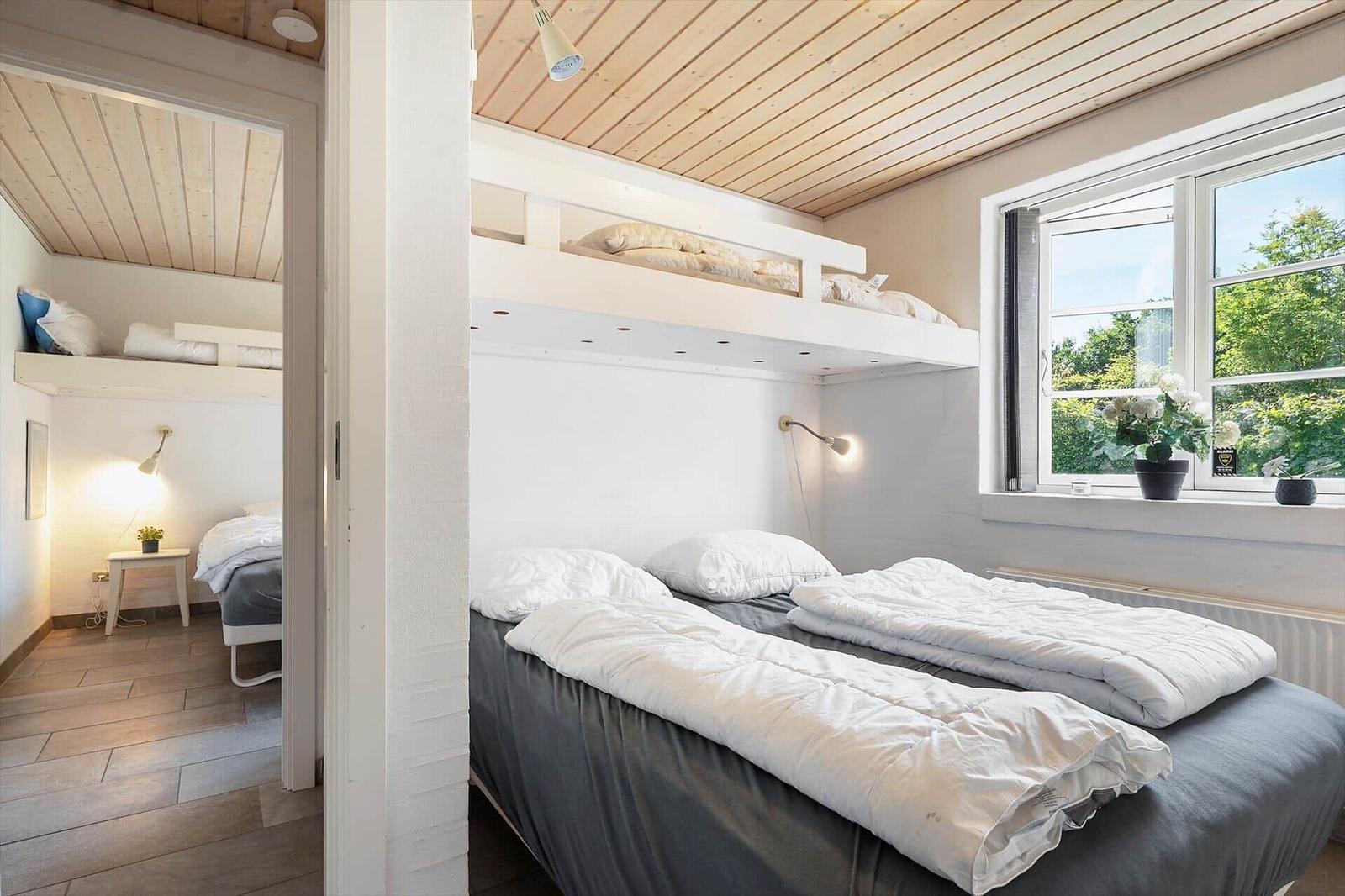 Zwei Räume mit Schlafbereich und Treppe. Kompass zeigt Richtung.