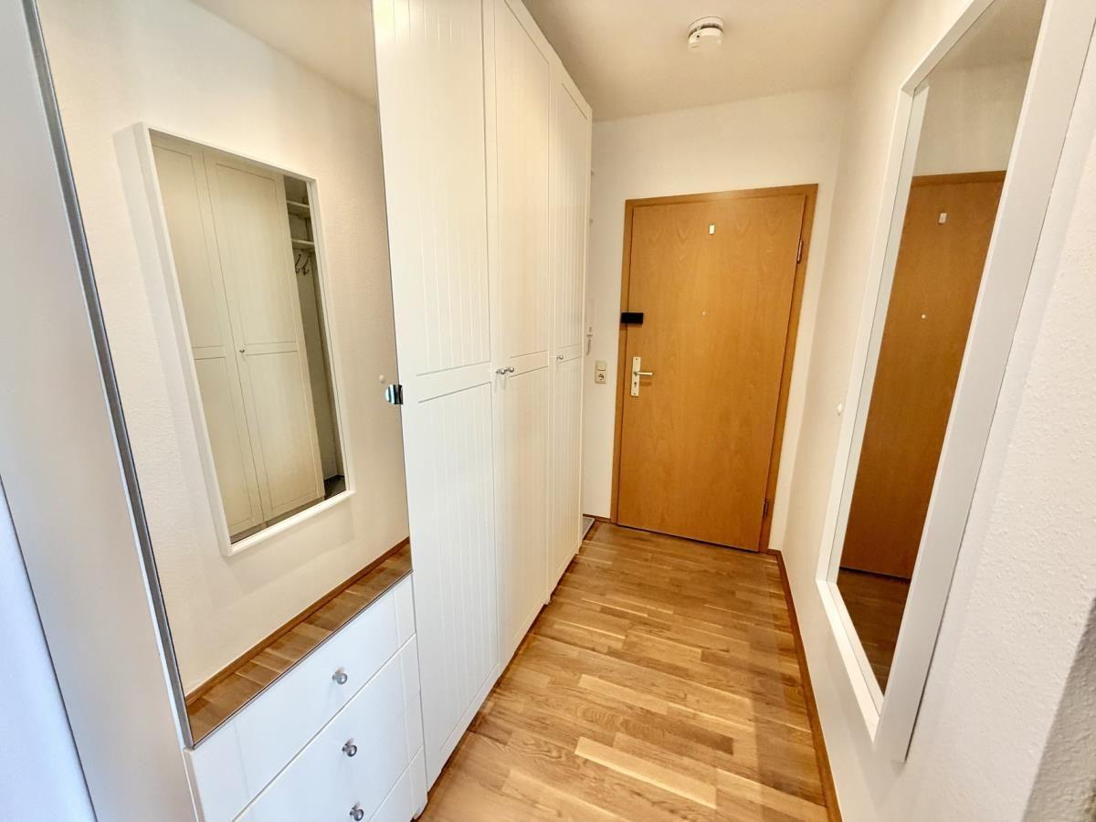 Badezimmer mit Dusche, Waschbecken und Toilette. Weiße Fliesen und Pflanze.