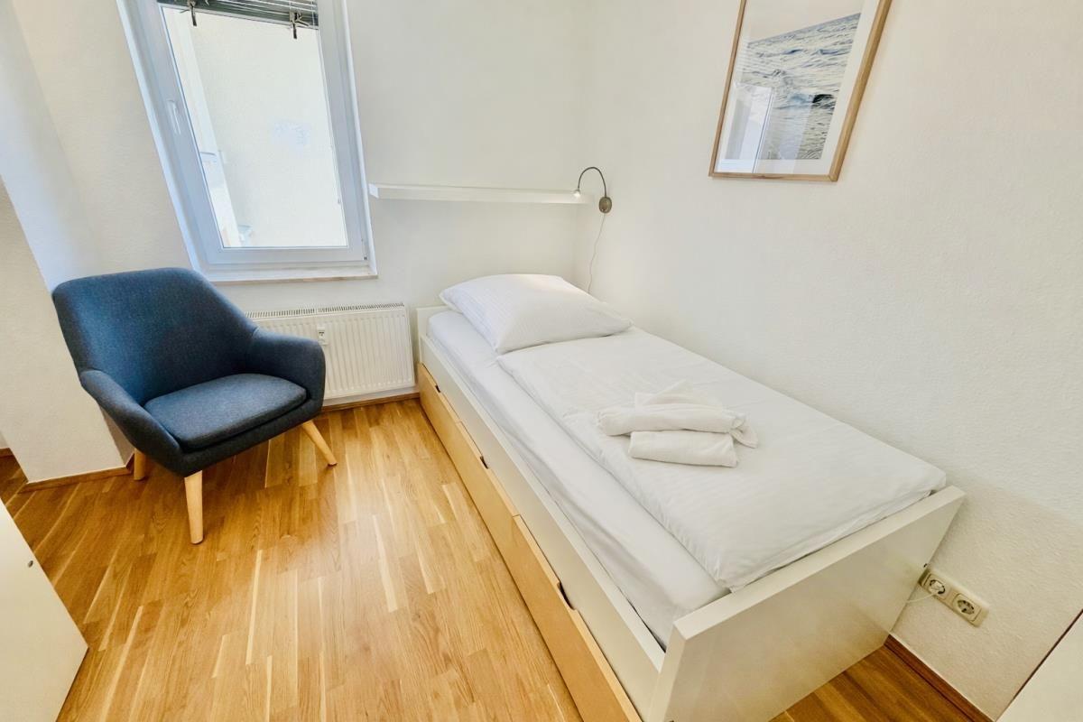 Ein Schlafzimmer mit einem Bett, einem Stuhl und einer Wandlampe.