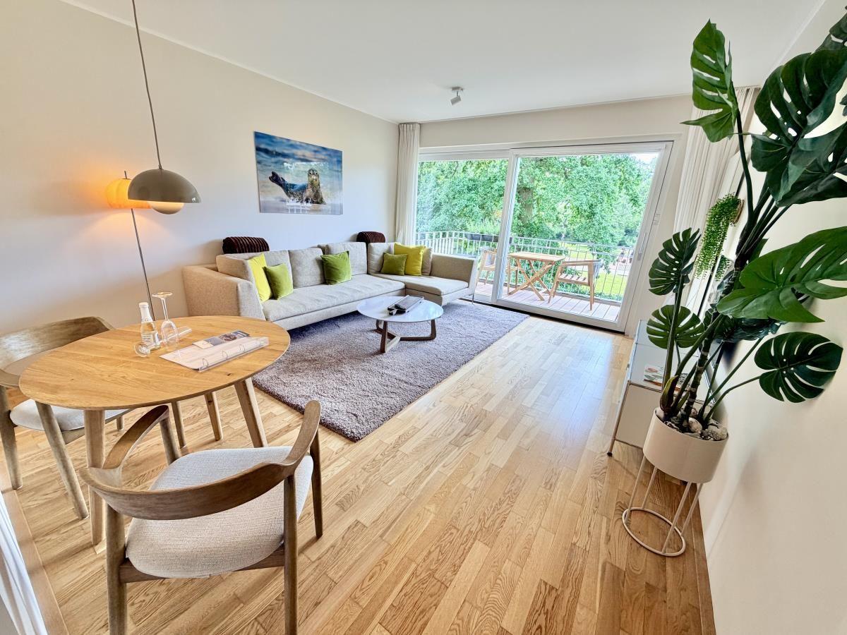 Schlafzimmer mit Doppelbett, blauem Kopfteil, Holzboden und Fenster mit Blick.