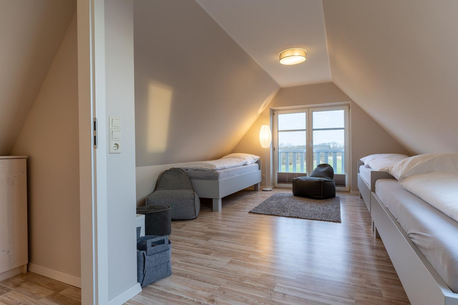 Zimmer mit zwei Betten, Fenster und Holzboden.