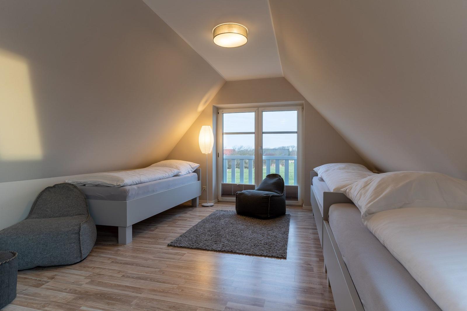 Zimmer mit zwei Betten, Bodenheizung und Balkonanschluss.