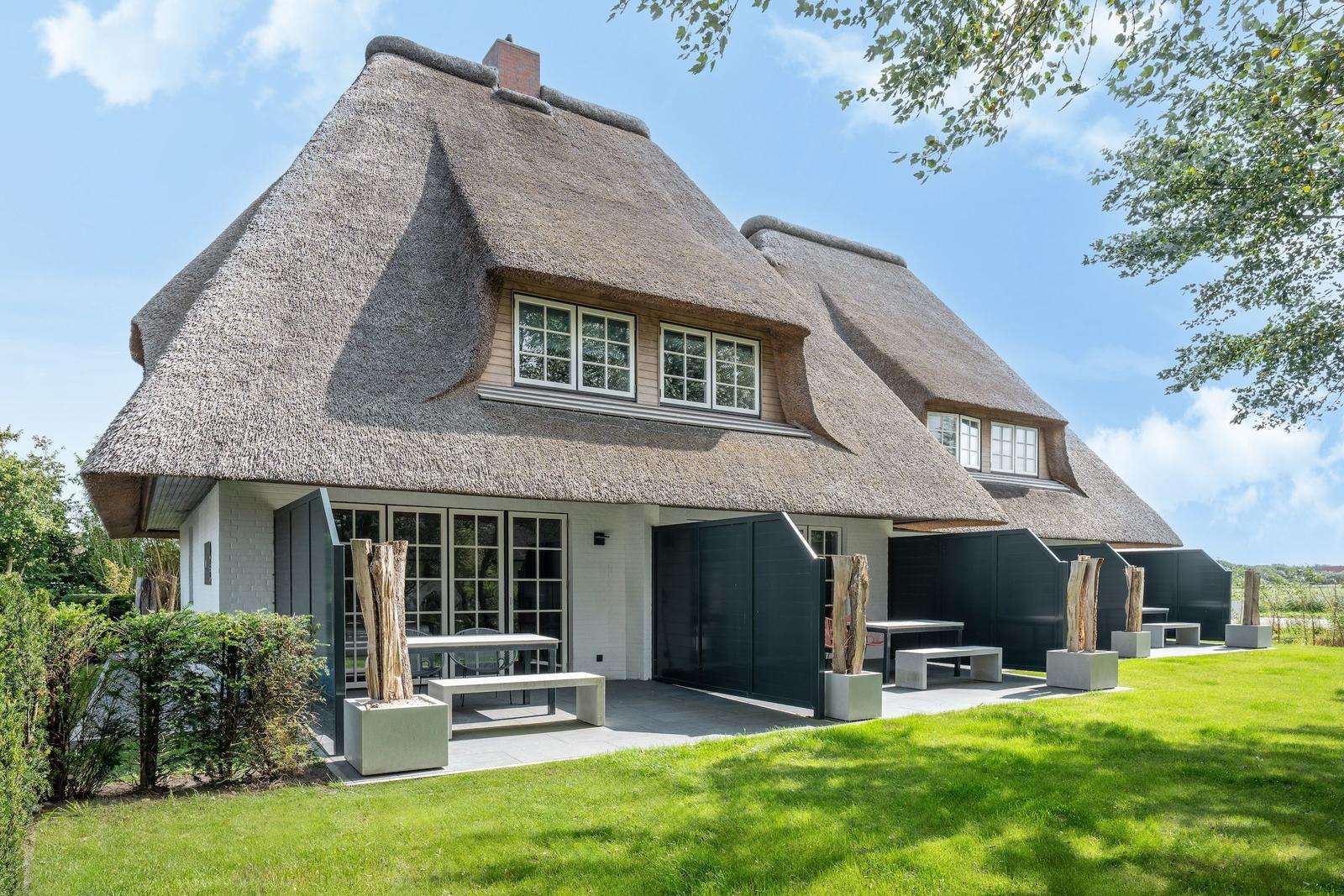 Haus mit Strohdach, Terrasse und Garten. Moderne Einrichtung im Freien.