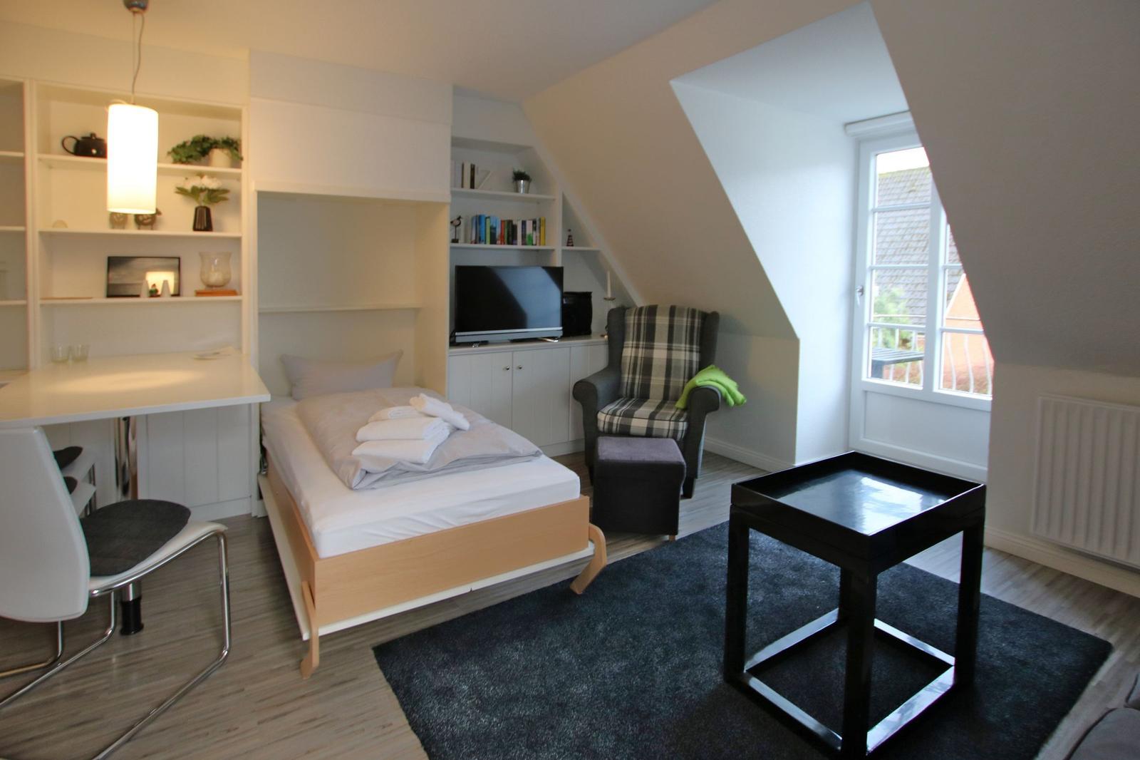 Upper floor with living, sleeping, kitchen, and bathroom. Balcony and open gallery.