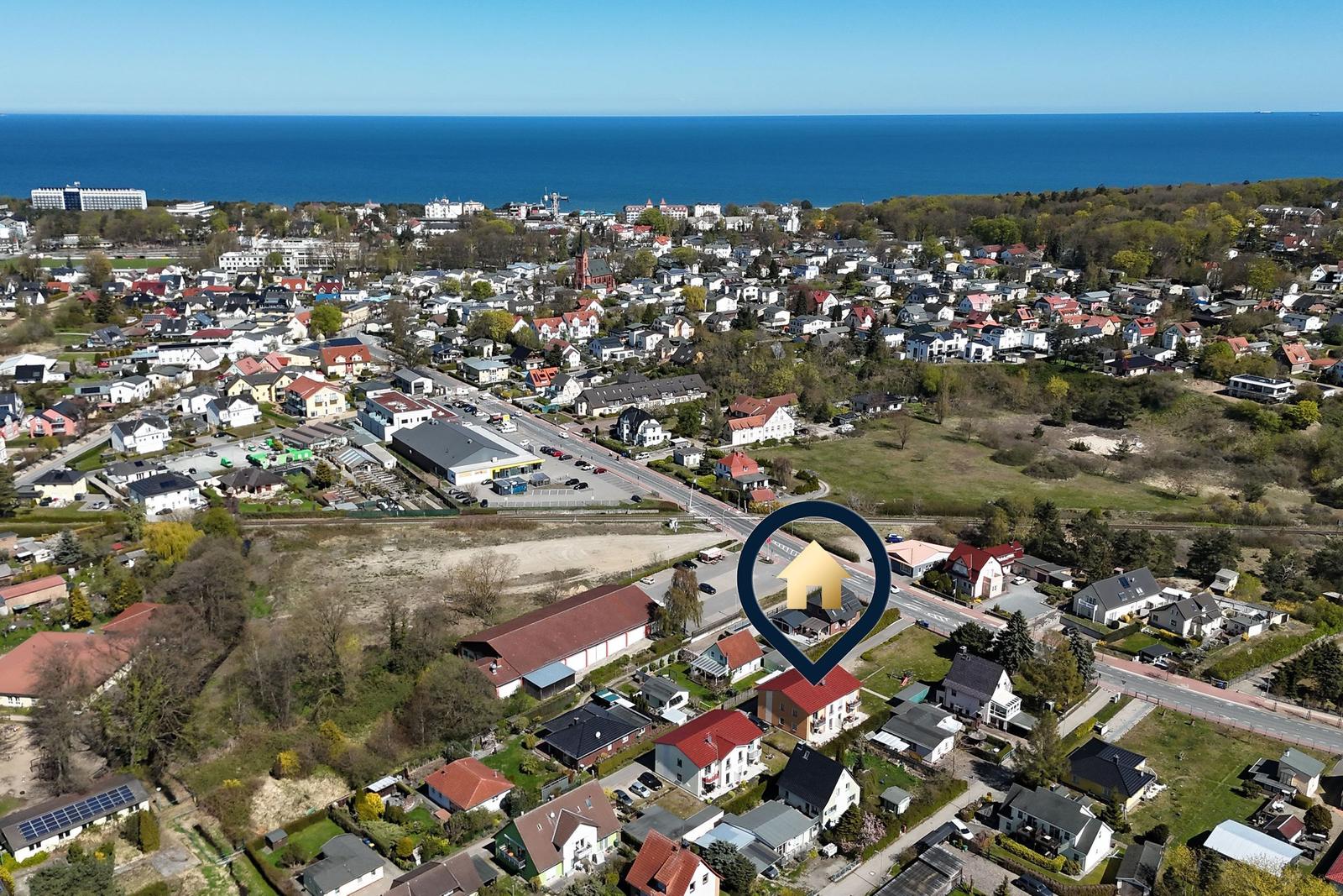 Holzbrücke führt über Wasser zu Strand und Hotels im Hintergrund.