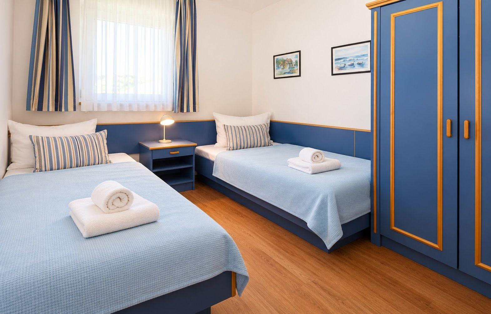 Schlafzimmer mit Doppelbett, blauen Nachttischen und Kleiderschrank.