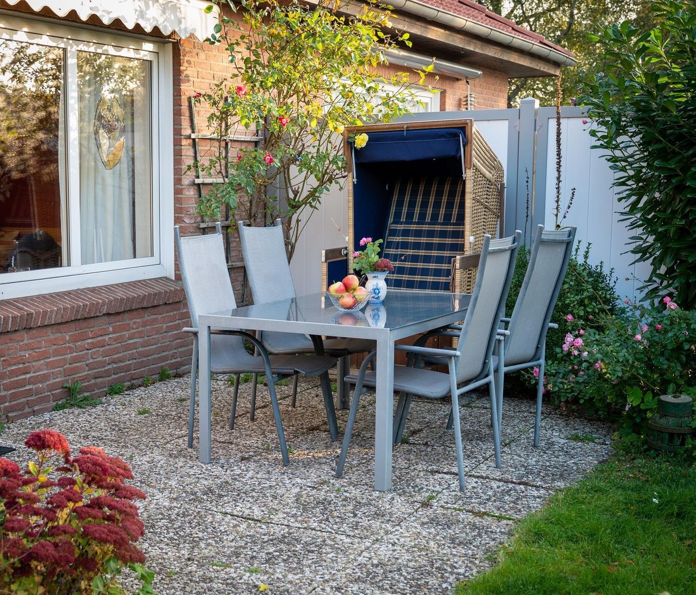 Ein Haus mit rotem Dach und beleuchtetem Eingangsbereich, umgeben von Grünflächen und Pflanzen.