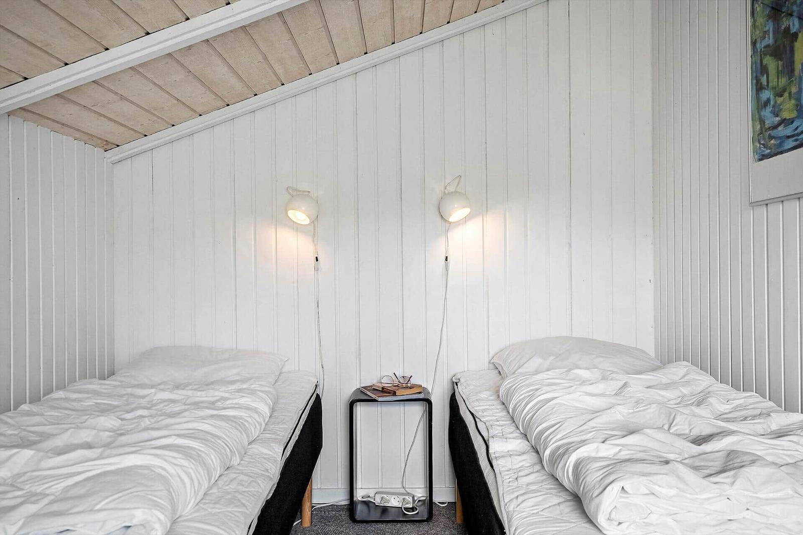 Wohn- und Essbereich mit Kamin, TV und Esstisch. Holzdecke und weiße Wände.