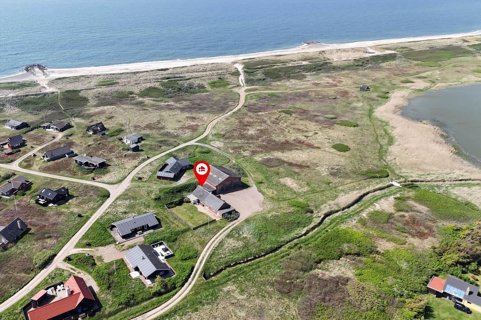 Luftbild von Ferienhäusern am Ufer eines Sees mit Grasland und Wegen.