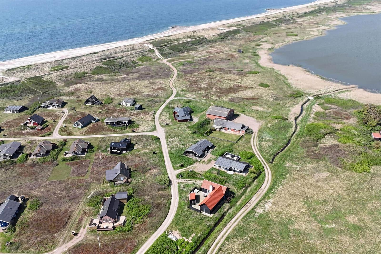 Aerial view of coastal village with houses and sandy beach.