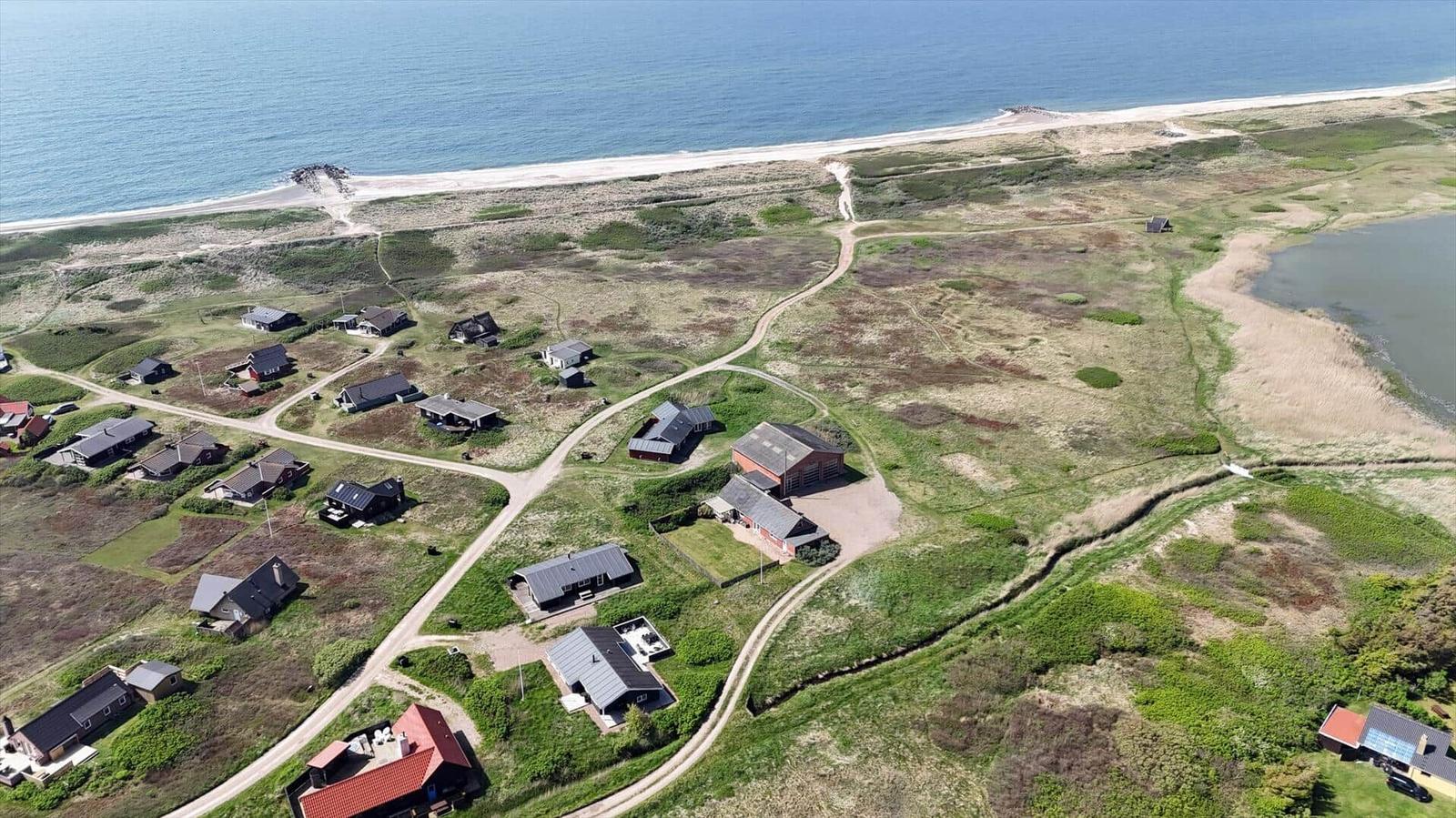 Haus mit rotem Dach in ländlicher Umgebung nahe Strand und See.