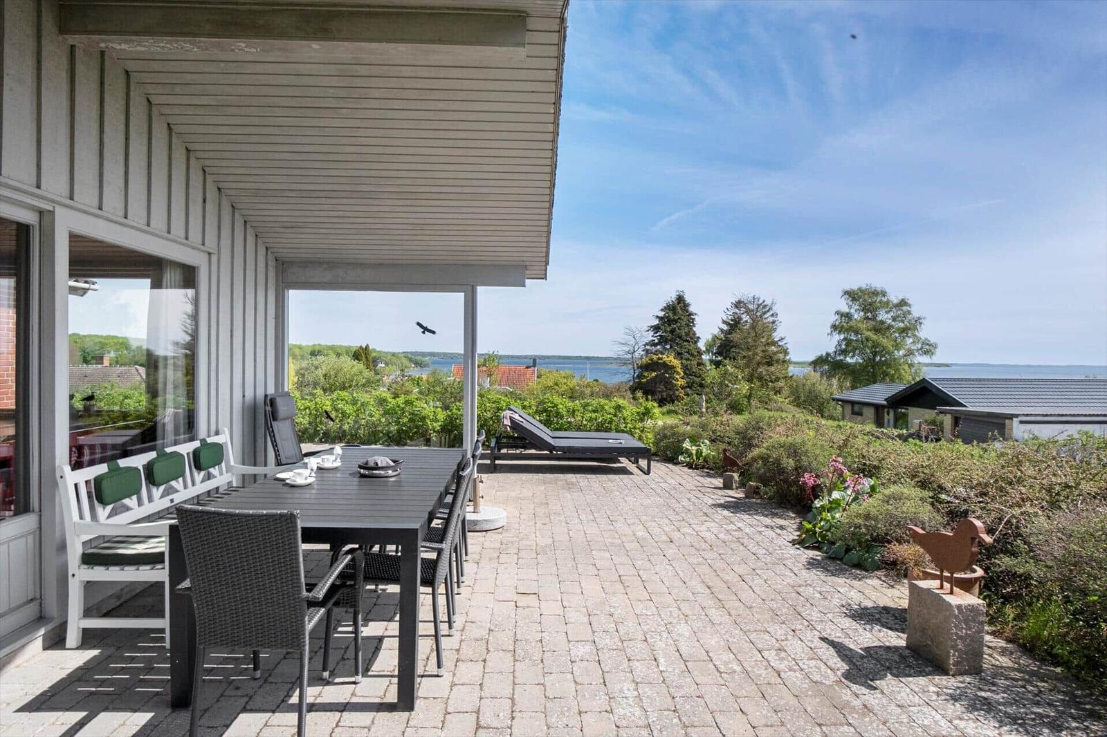 Moderne Ferienhaus mit Terrasse, Grill und Garten. Blick auf grüne Landschaft.