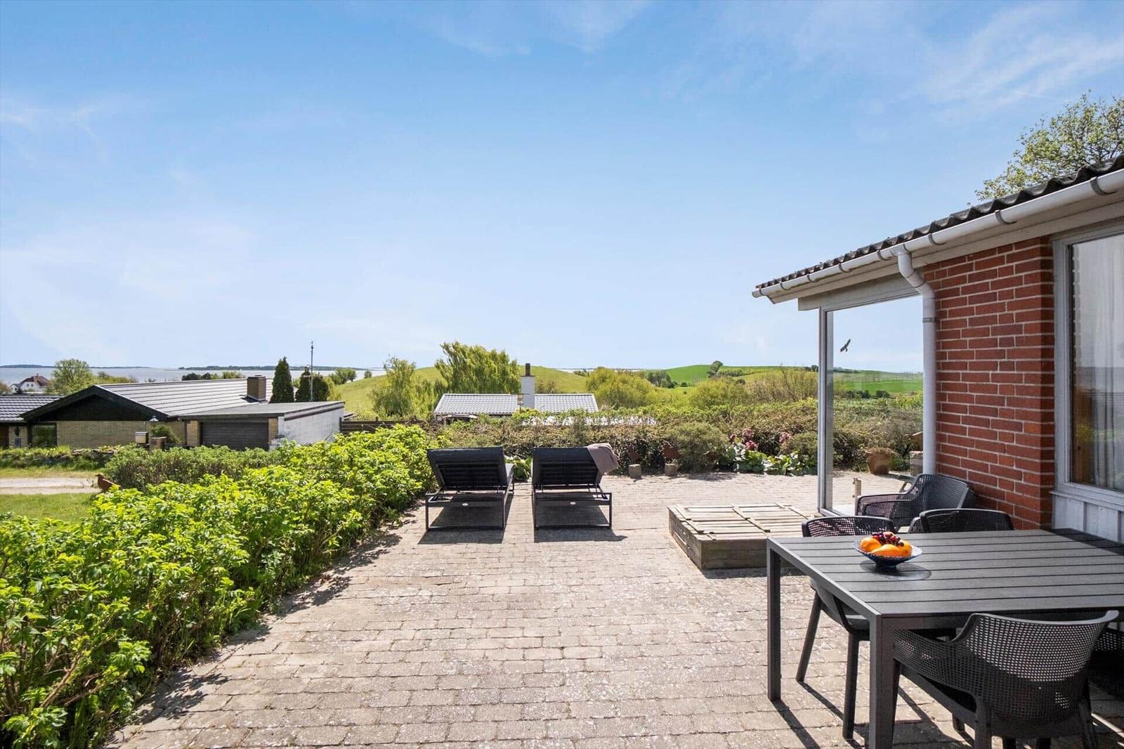 Terrasse mit zwei Stühlen, Blick auf grünen Garten und Himmel.