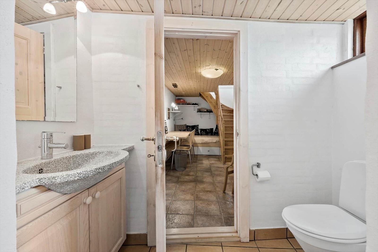 Badezimmer mit Waschbecken, Toilette und Blick in Schlafzimmer