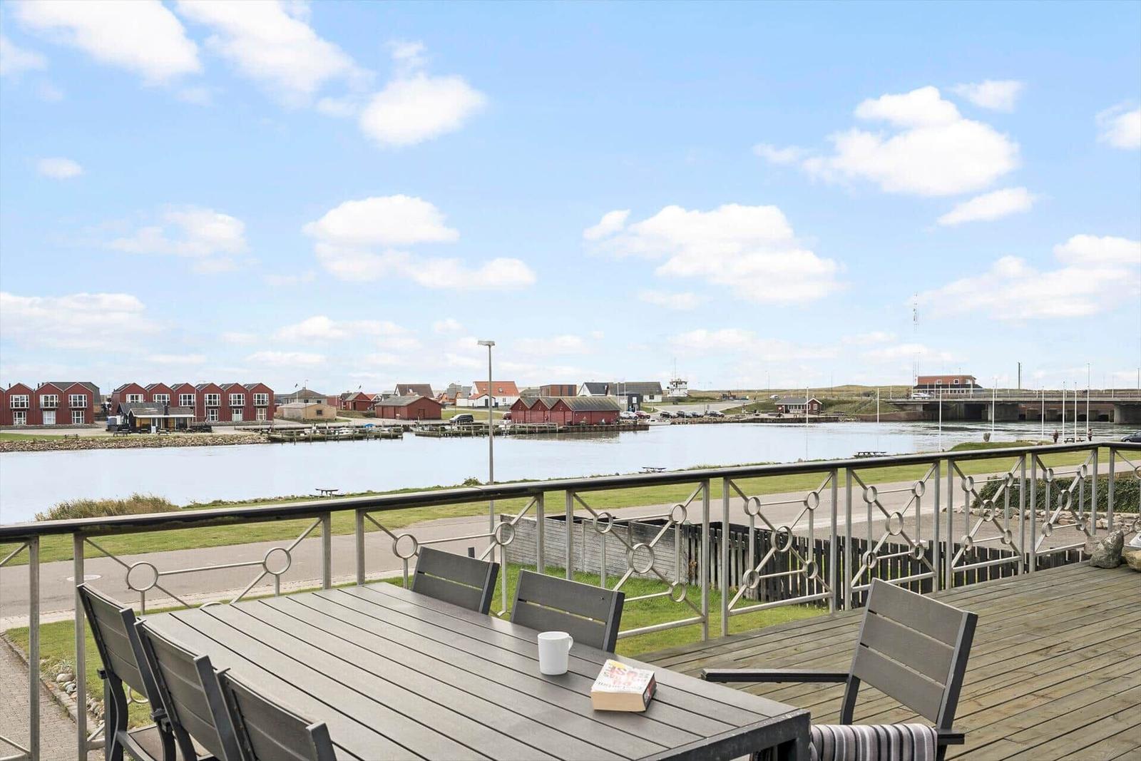 Terrasse mit Tisch und Stühlen, Blick auf Wasser und Häuser.