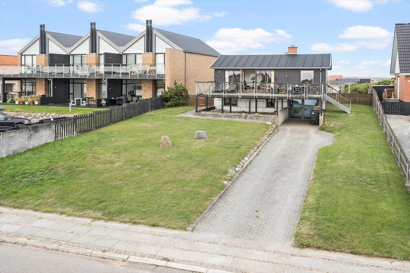 Moderne Ferienhaus mit Terrasse und Garten. Zugang über gepflasterten Weg.