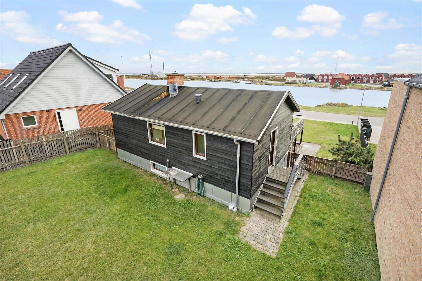 Ein kleines Haus mit Garten und Blick auf Wasser.