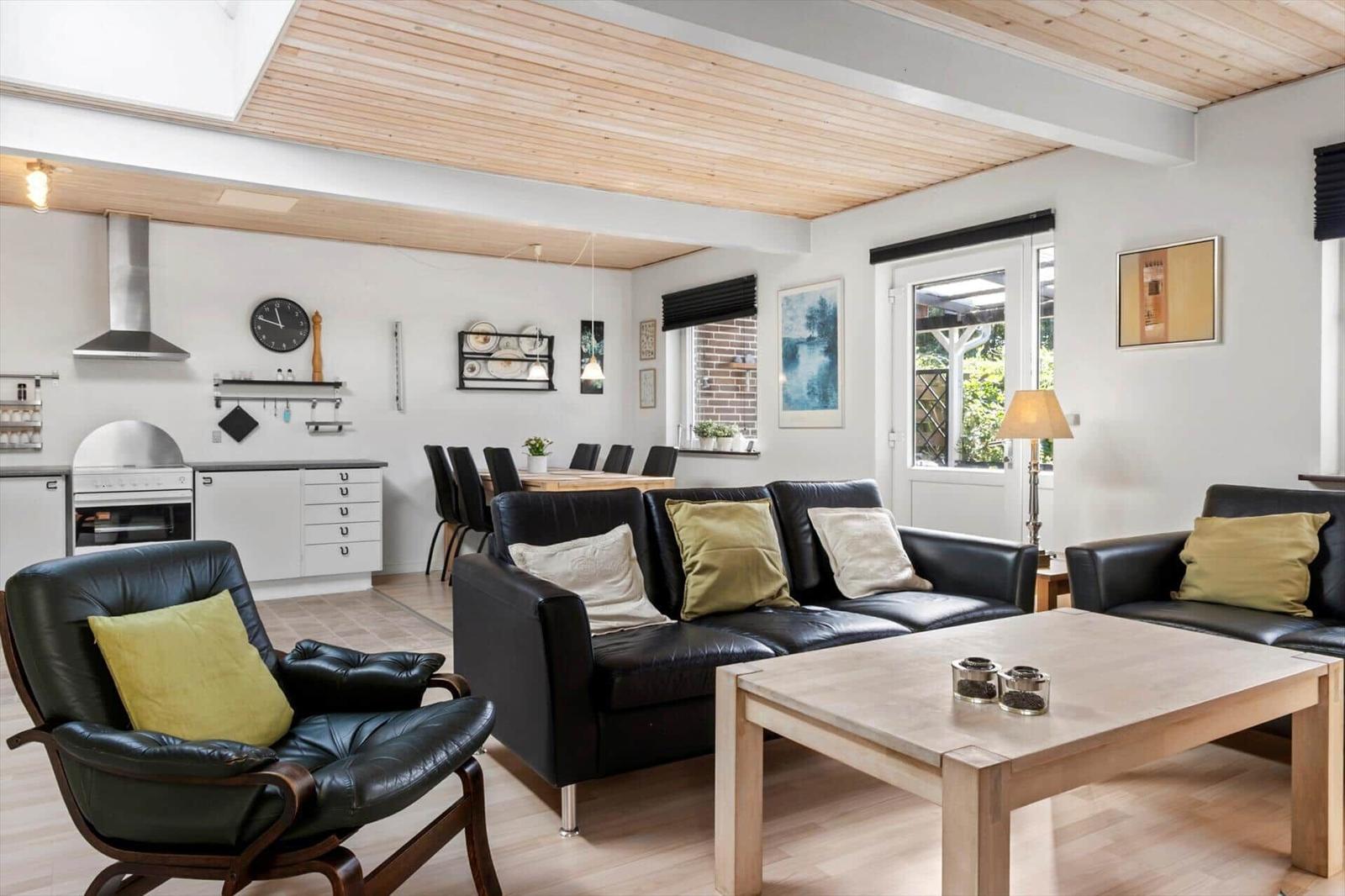 Terrasse mit zwei Sesseln und einem Sofa vor einer Backsteinwand mit Bildern.