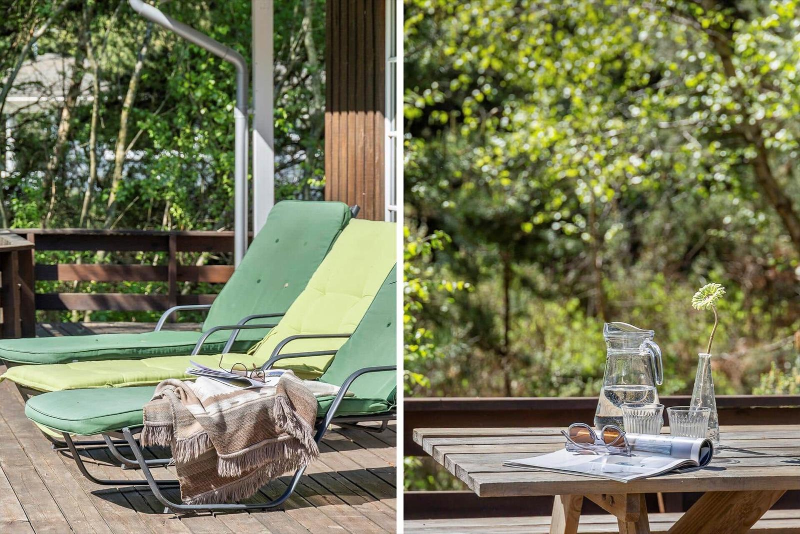 Terrasse mit Tisch und Stühlen, Holzwand und offener Tür zum Innenraum.