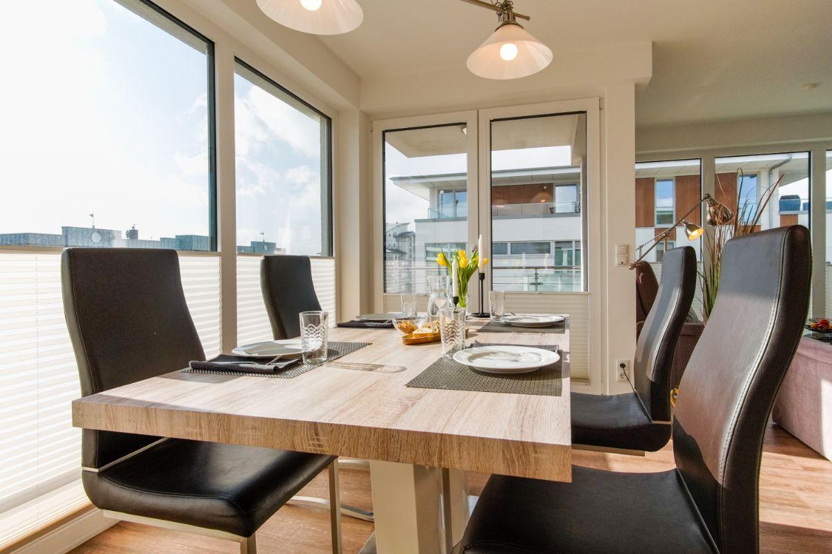 Tisch mit gelben Tulpen, Gläsern und Kerzen im Hintergrund.