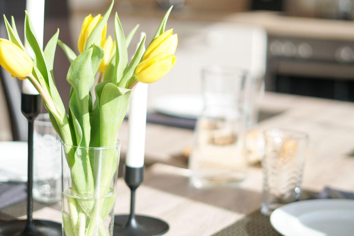 Gedeckter Esstisch mit Blumen, Gläsern und Brot.