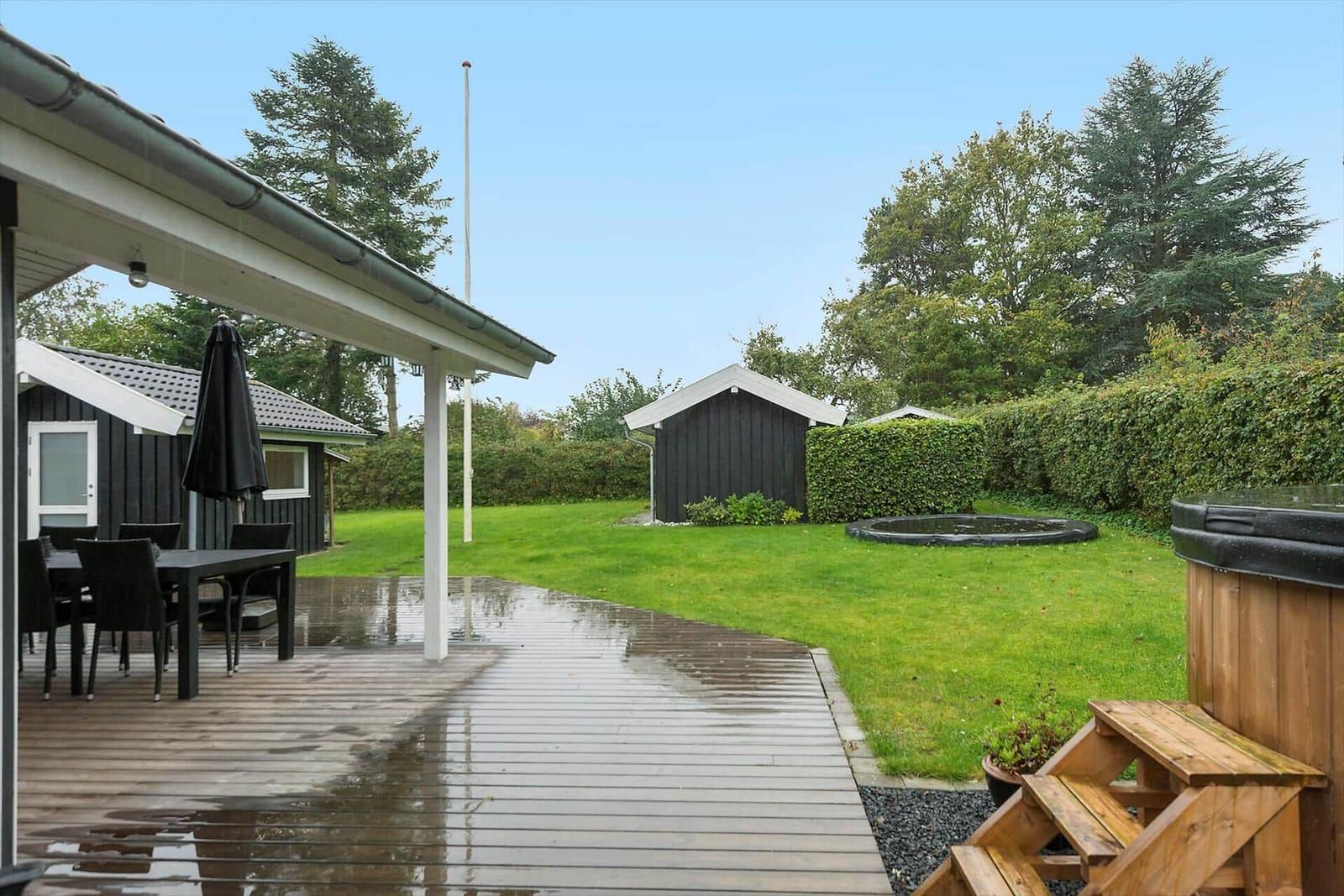 Terrasse mit Tisch und Stühlen, Holzweg, Garten, Whirlpool und Schuppen.
