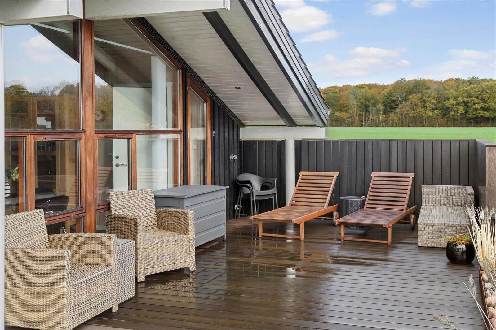 Terrasse mit Grill, Tisch und Stühlen. Blick ins Innere des Hauses.