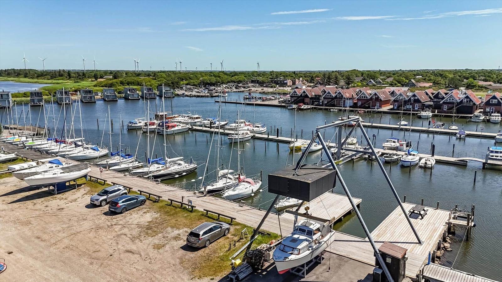 Hafen mit Booten, Steg und Windkraftanlagen im Hintergrund.