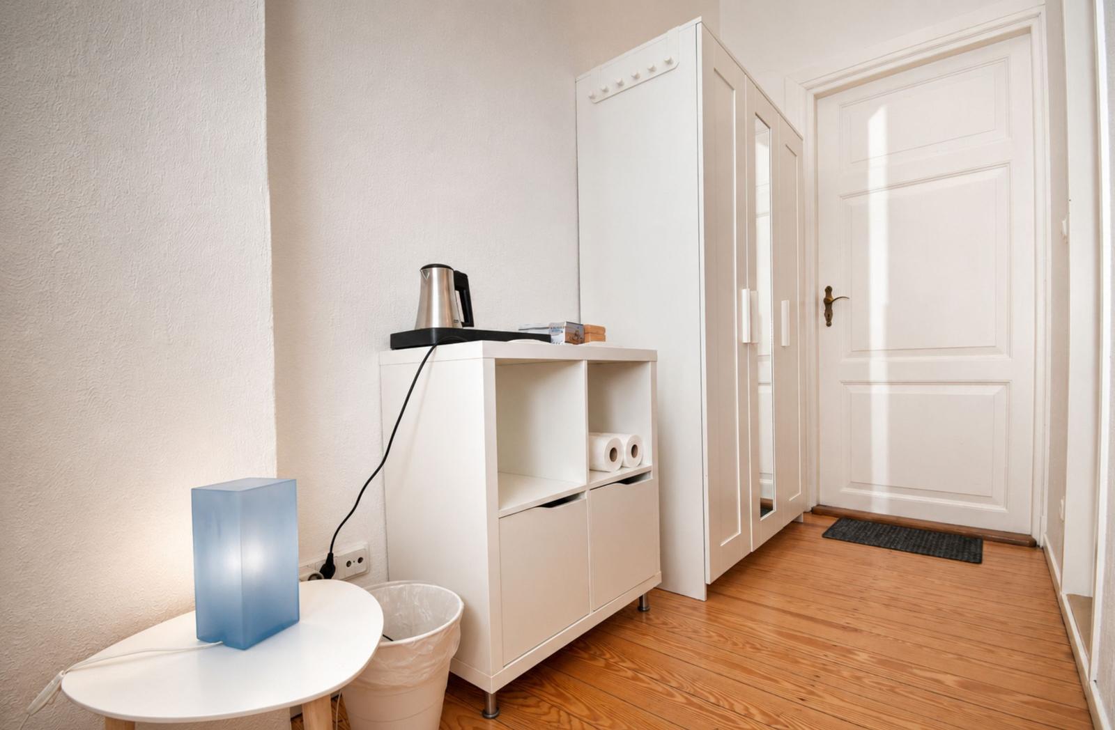 Zimmer mit Bett, Schrank und integriertem Bad mit Dusche und Toilette.