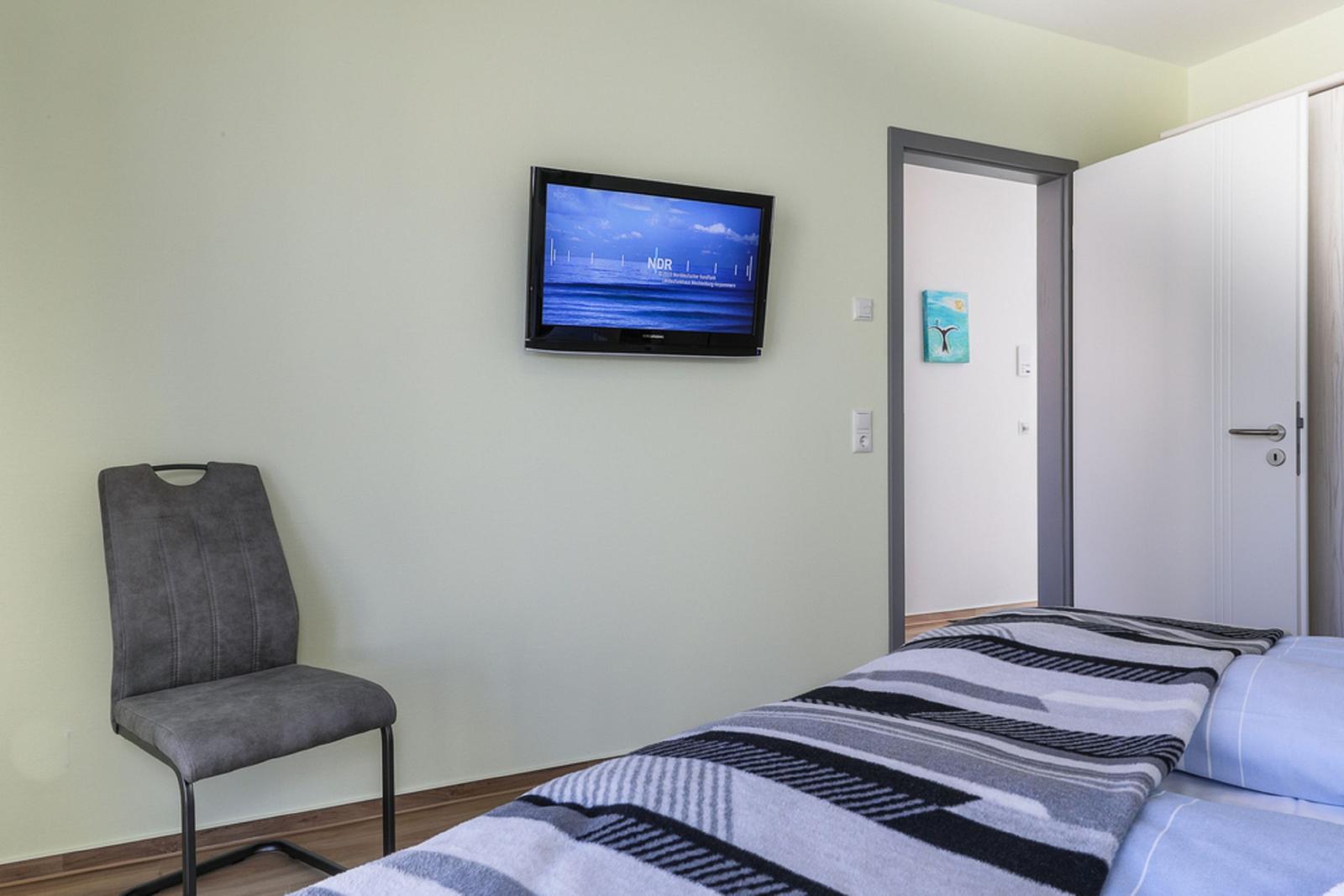 Badezimmer mit Waschbecken, Spiegel, Handtuchhalter und Fenster.