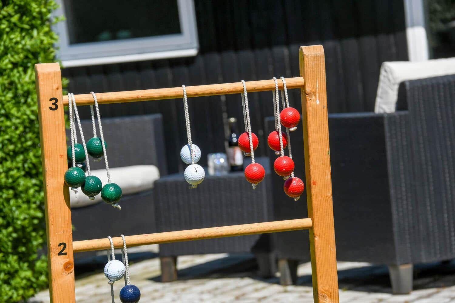 Terrasse mit Tischen und roten Sonnenschirmen am Hafen. Blaues Boot liegt im Wasser.