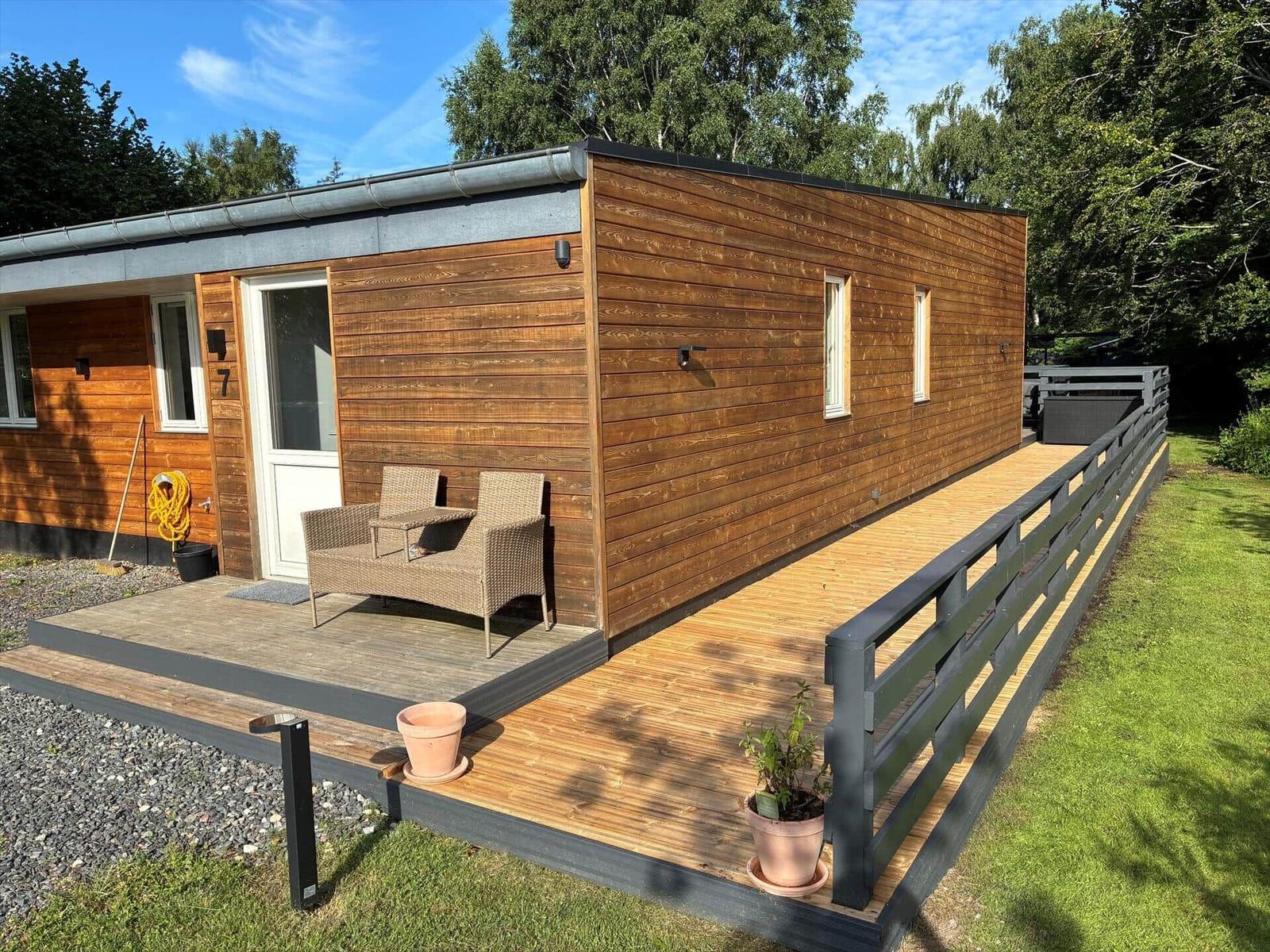 Esszimmer mit Holztisch, Stühlen und Wickerlampen. Durchgang zur Küche und Wohnbereich.