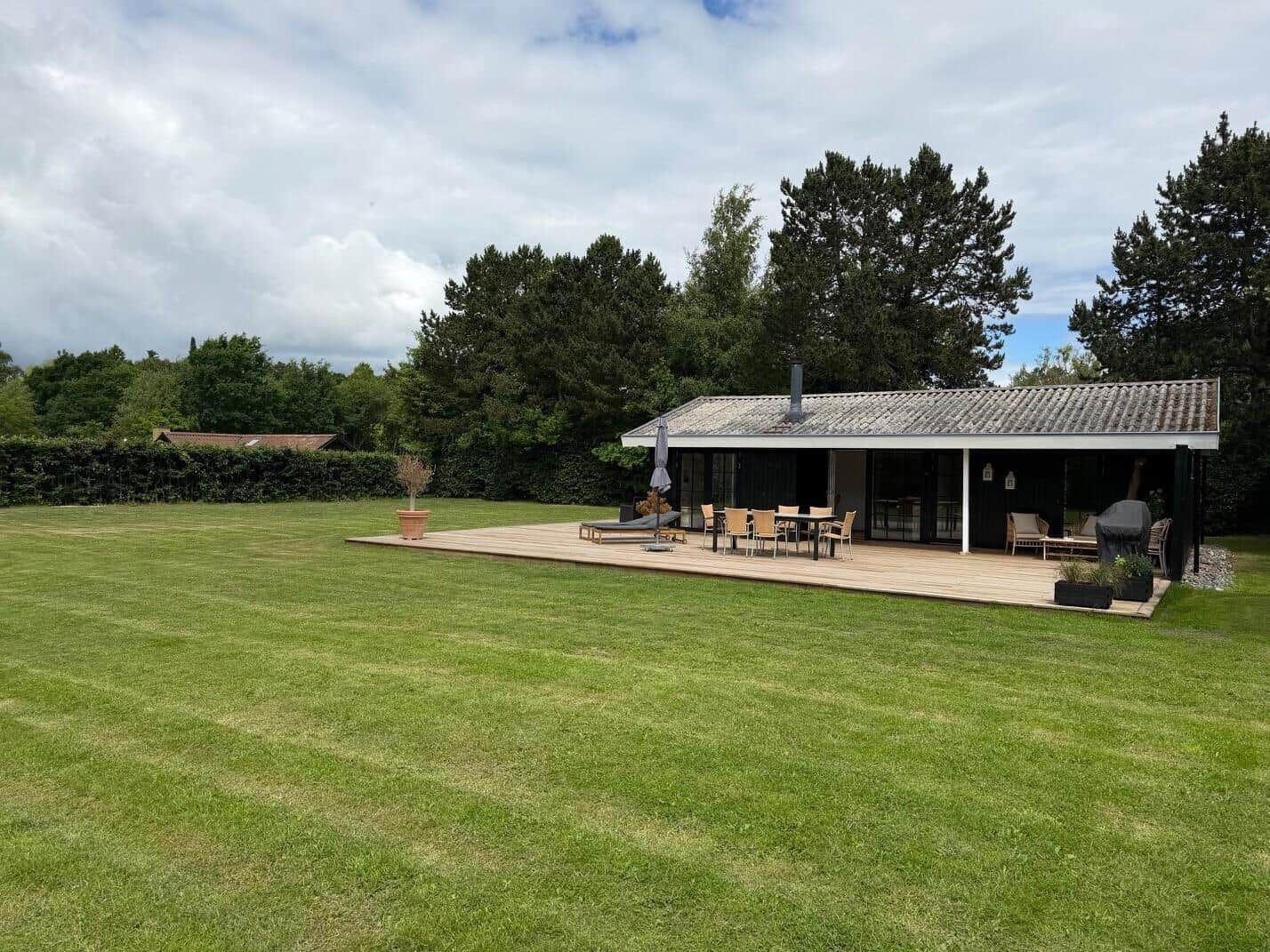 Haus mit Terrasse, Garten und Sitzgelegenheiten im Freien.