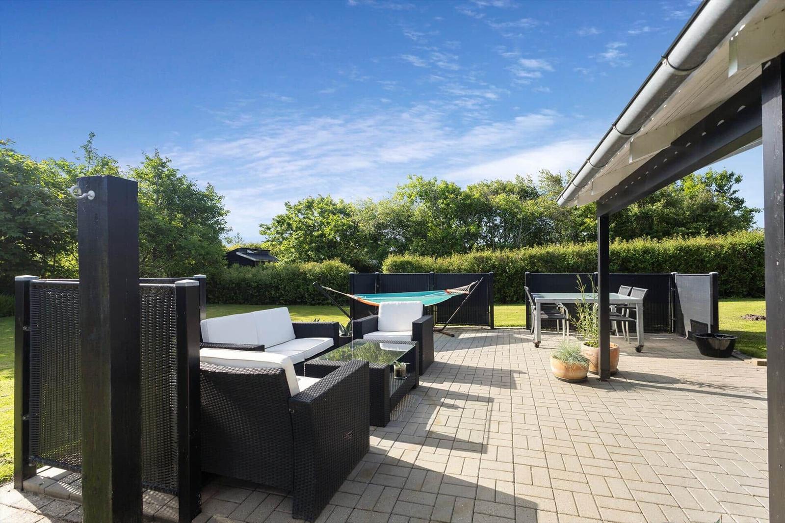 Schwarzes Haus mit großem Garten und Terrasse. Blick auf Meer und Himmel.