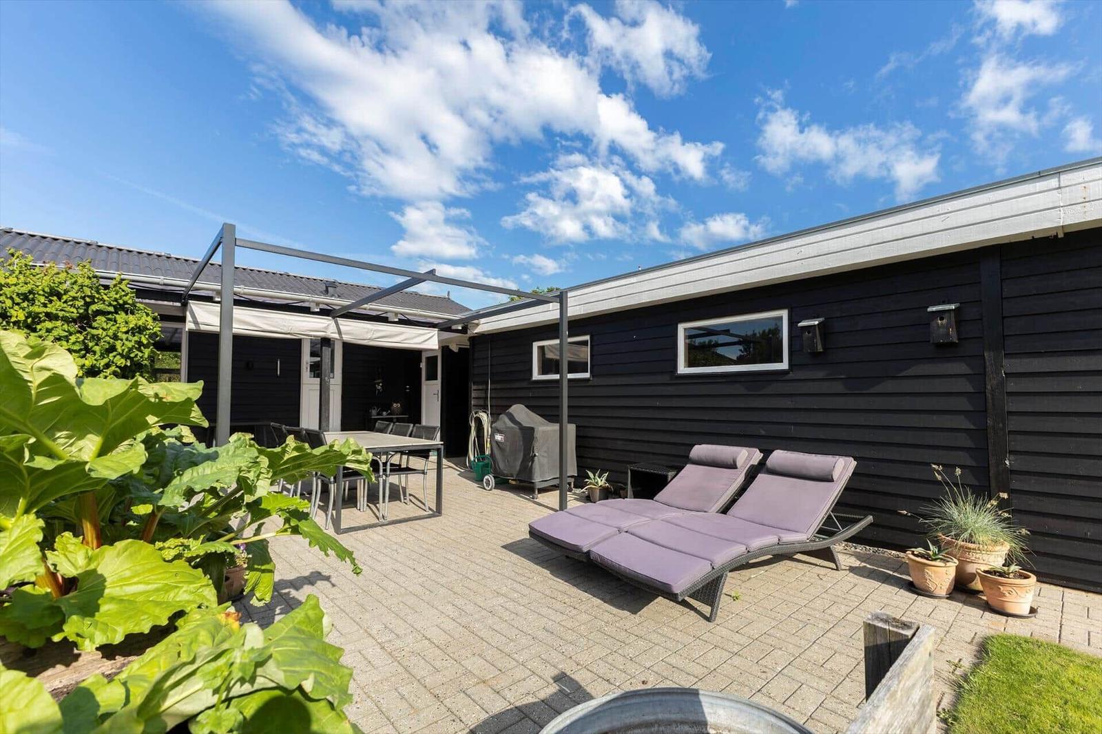 Terrasse mit Sitzgruppe, Tisch, Hängematte und Blick auf den Garten.