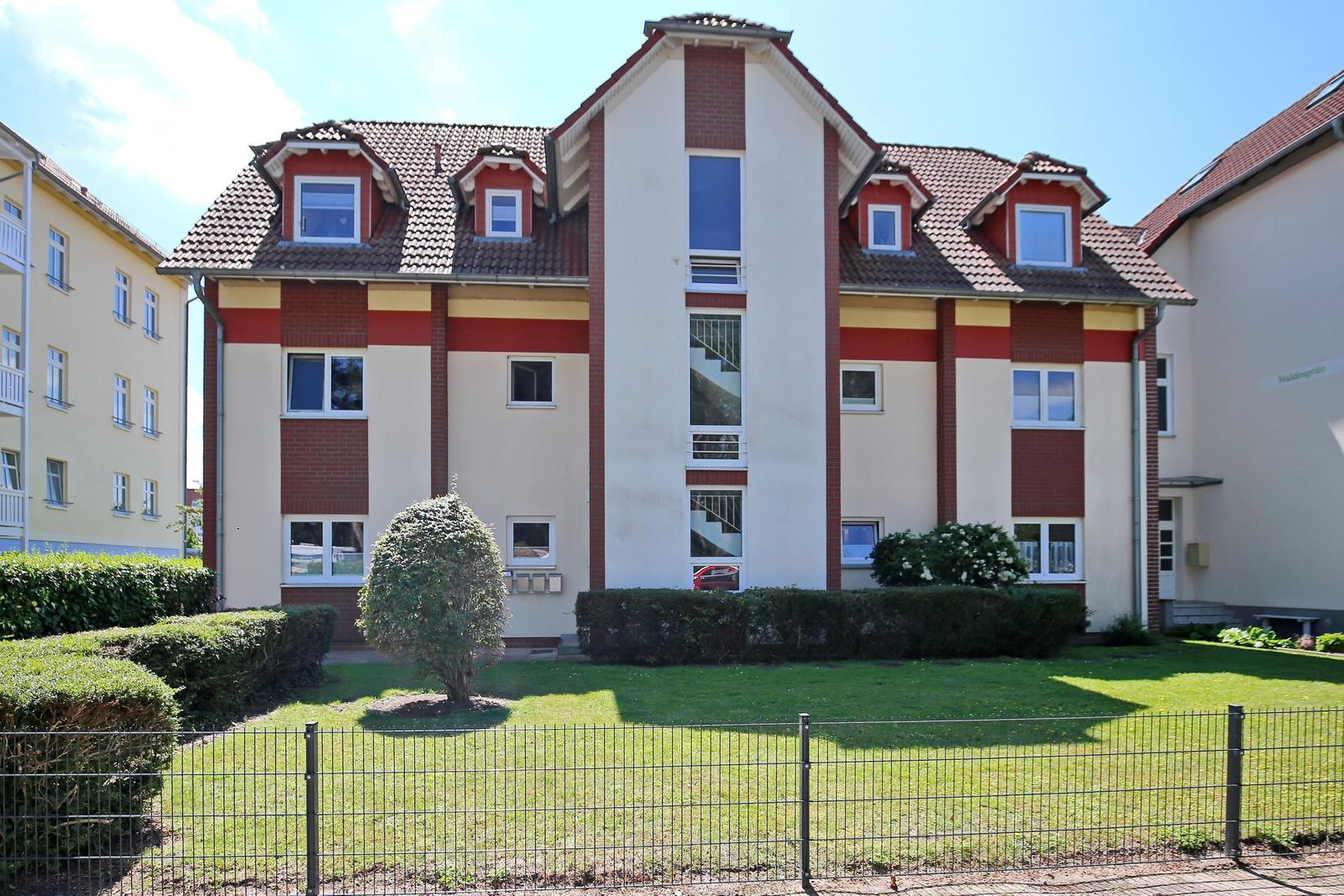 Haus mit Garten und Dachfenstern. Fassade in Weiß, Rot und Gelb.