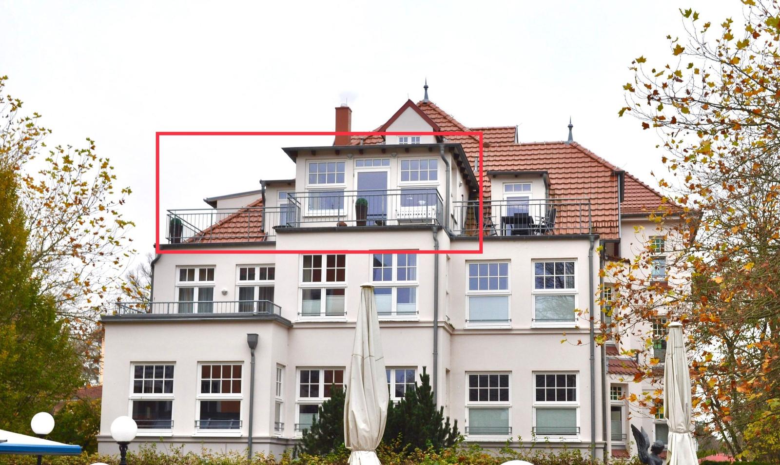 Dachgeschoss mit Balkon und Fenstern, rote Dachziegel, weiße Fassade.
