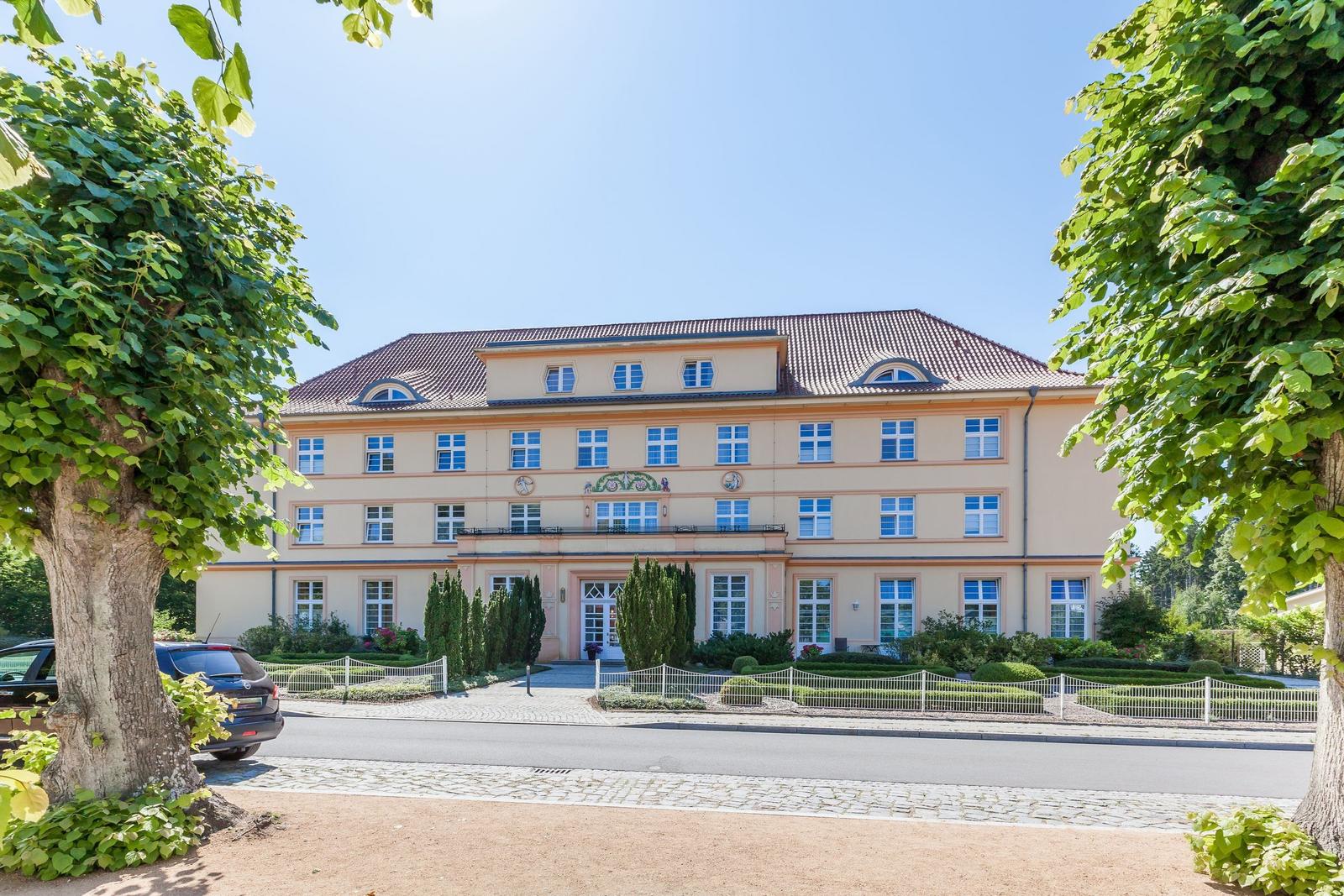 Ein großes, hellfarbenes Gebäude mit rotem Dach und gepflegtem Garten.