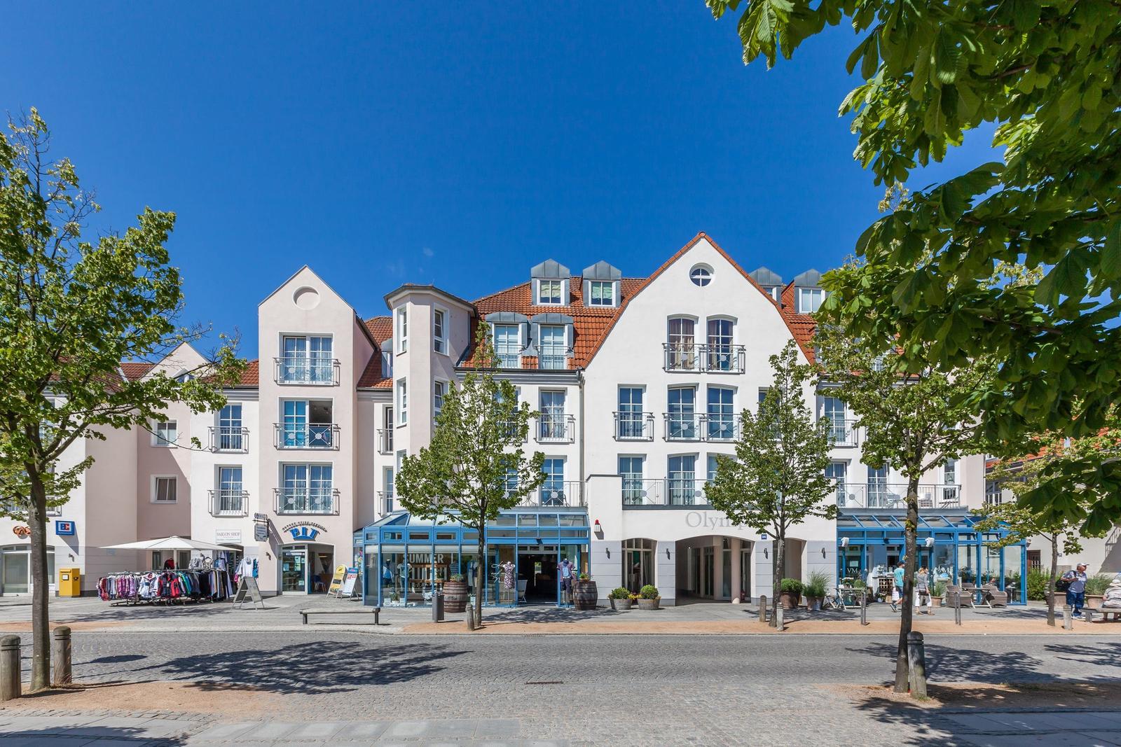 Wohnhaus mit Balkonen und rotem Dach unter blauem Himmel