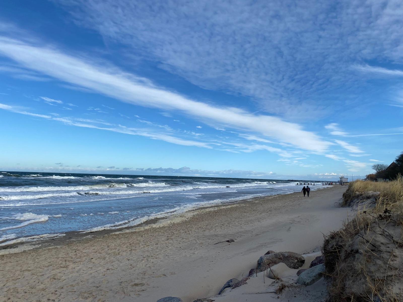Pfad zur Strandkörbe, roter Dachbereich, Sandstrand und Meer im Hintergrund.